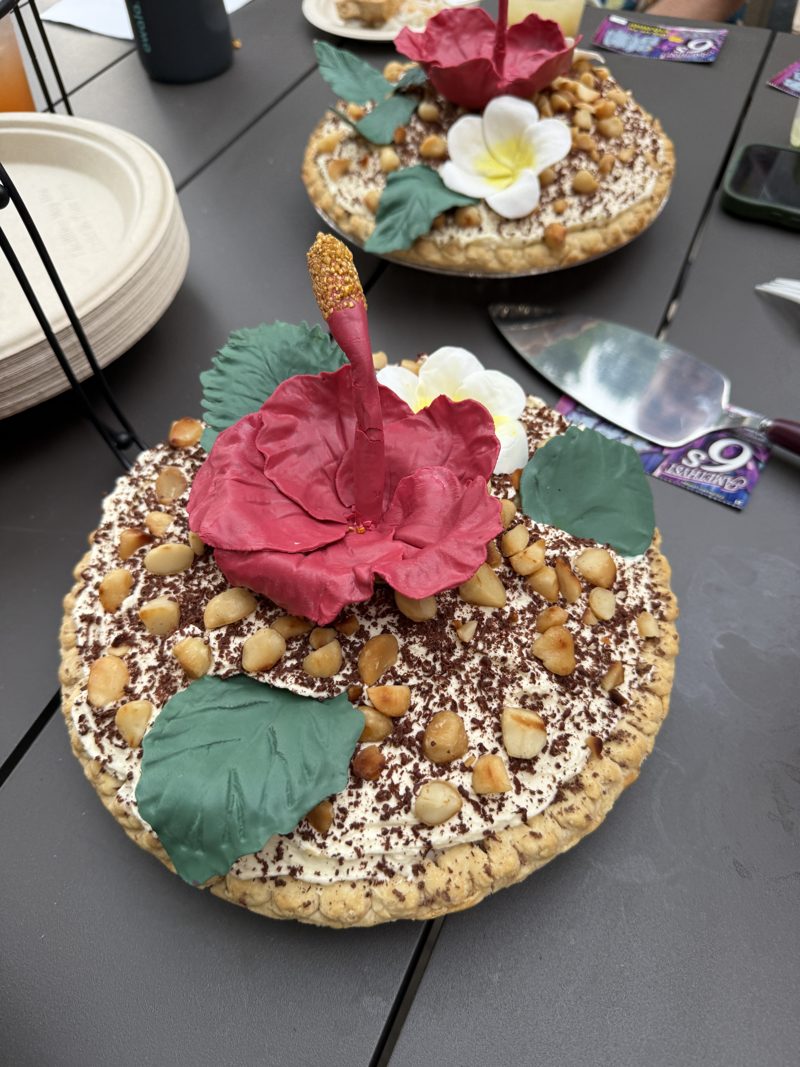 Two cream pies topped with macadamia nuts, shaved chocolate, a red sugar hibiscus and a white plumeria